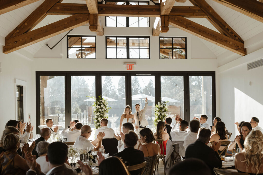 Wedding couple addressing guests during reception in front of large windows at Old Greenwood