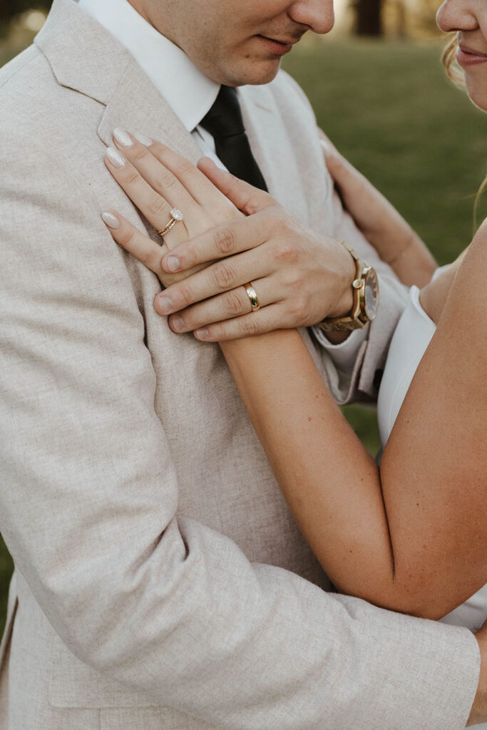Wedding couple's hands holding each other while wearing wedding rings at Old Greenwood