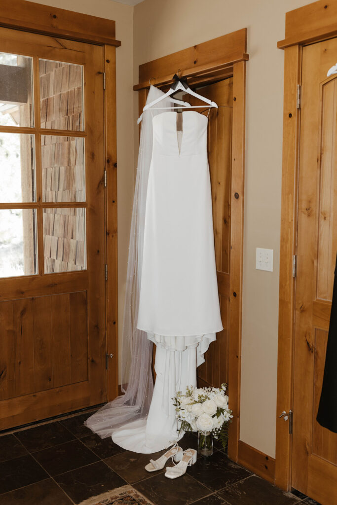 Wedding dress hanging on white hangar in wooden doorway at Old Greenwood