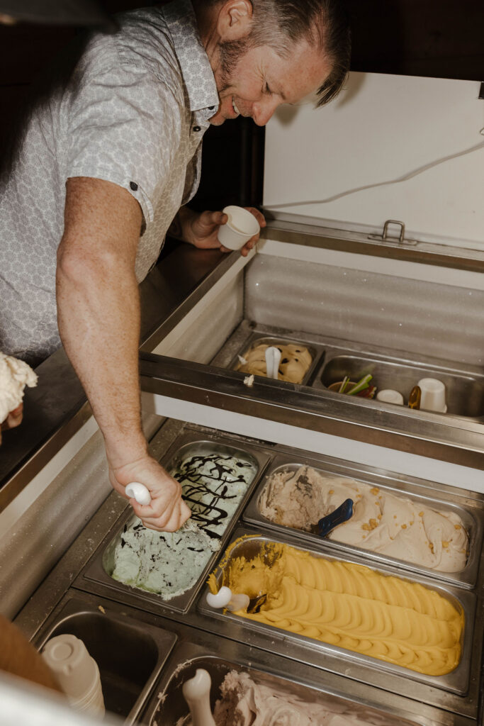 Wedding guests scooping ice cream out of tubs during reception at Timbers at Old Greenwood