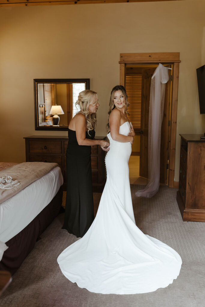 Bride's mom buttoning the back of bride's wedding dress inside at Timbers at Old Greenwood