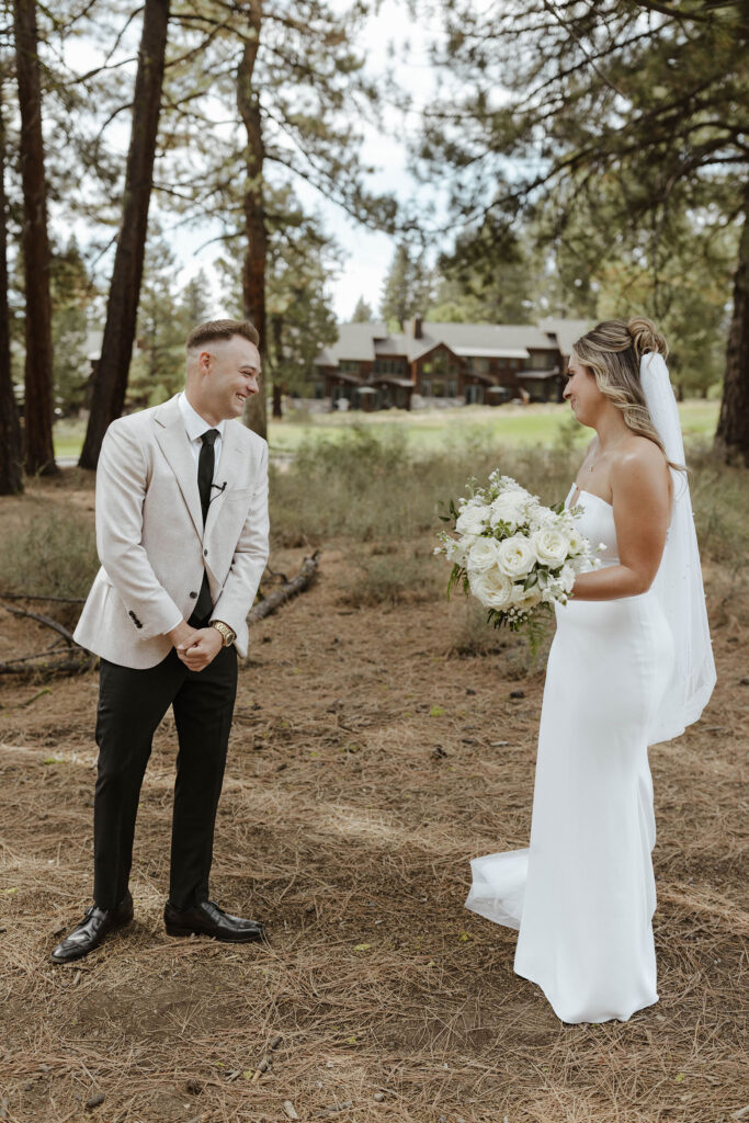 Groom smiling and reacting to wedding bride during first look outside at Timbers at Old Greenwood