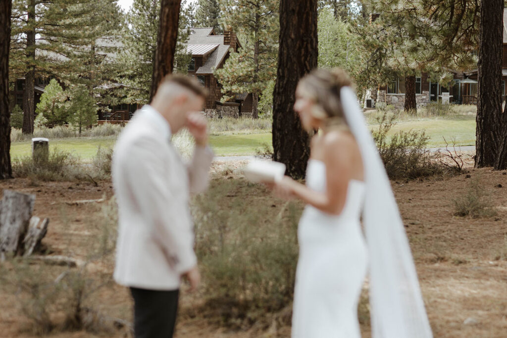 Groom emotional while bride is reading wedding vows outside in front of pine trees at Old Greenwood