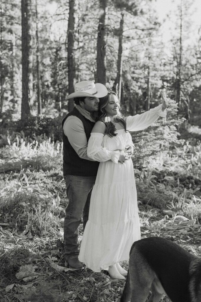 Man hugging fiancé from behind while she holds her hand up and both admire engagement ring in Truckee