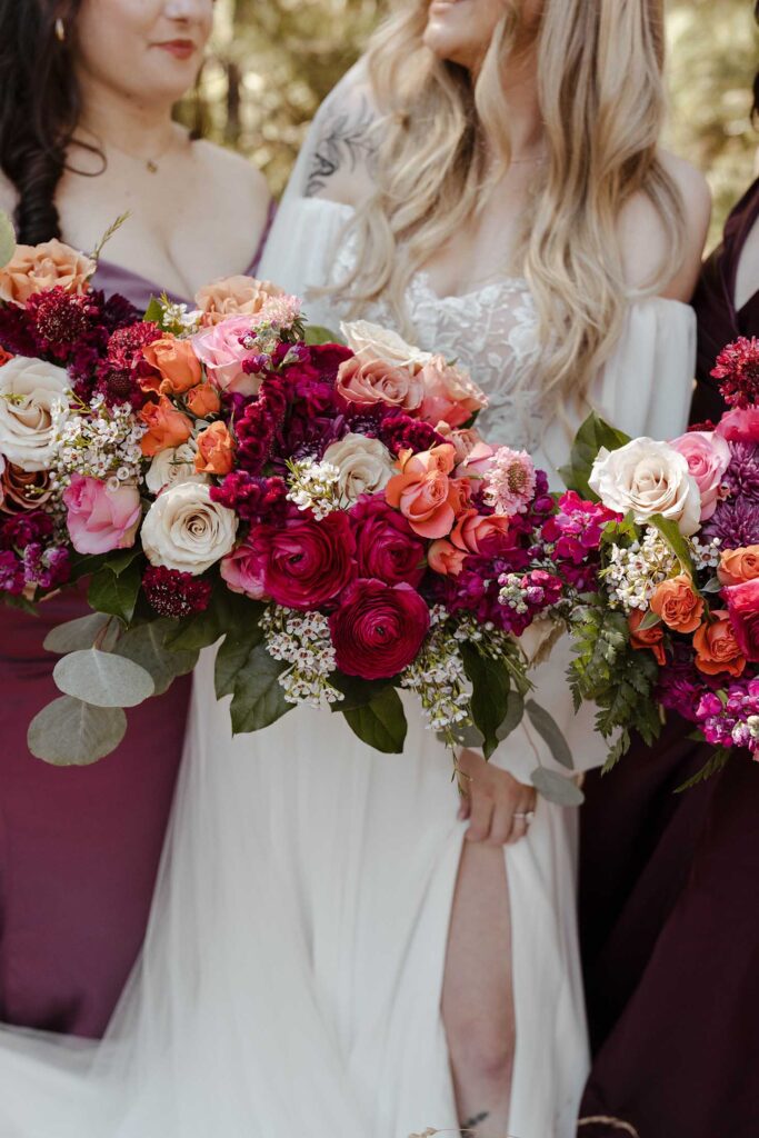 Close up of bride and bridesmaids holding colorful floral bouquets at Valhalla 