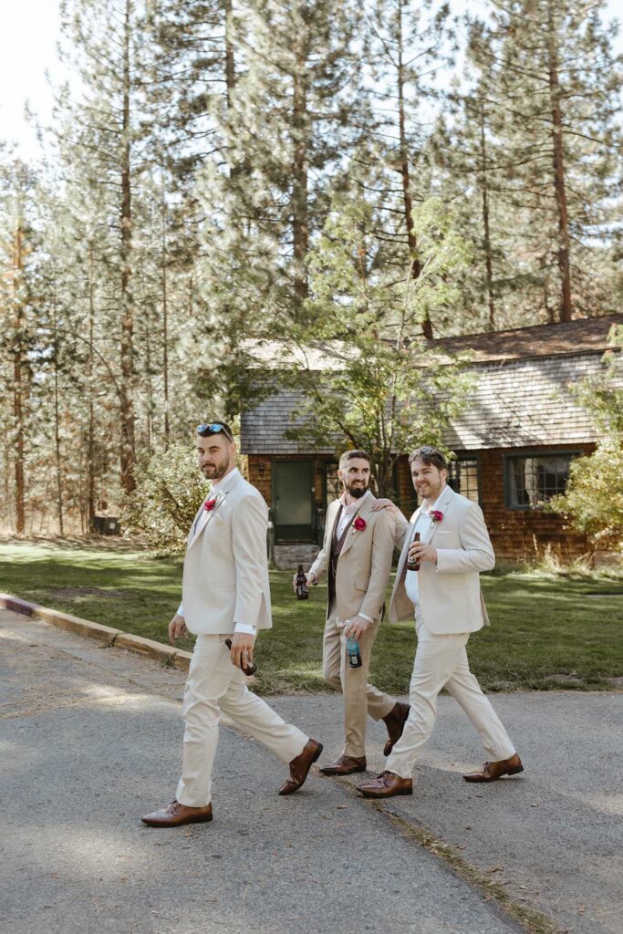 Groom and groomsmen in wedding attire walking across pathway with grass in background at Valhalla in Lake Tahoe