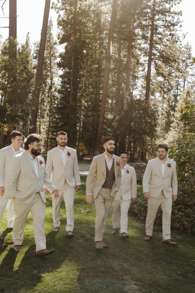 Wedding groom and groomsmen smiling and walking across grassy field at Valhalla in Lake Tahoe