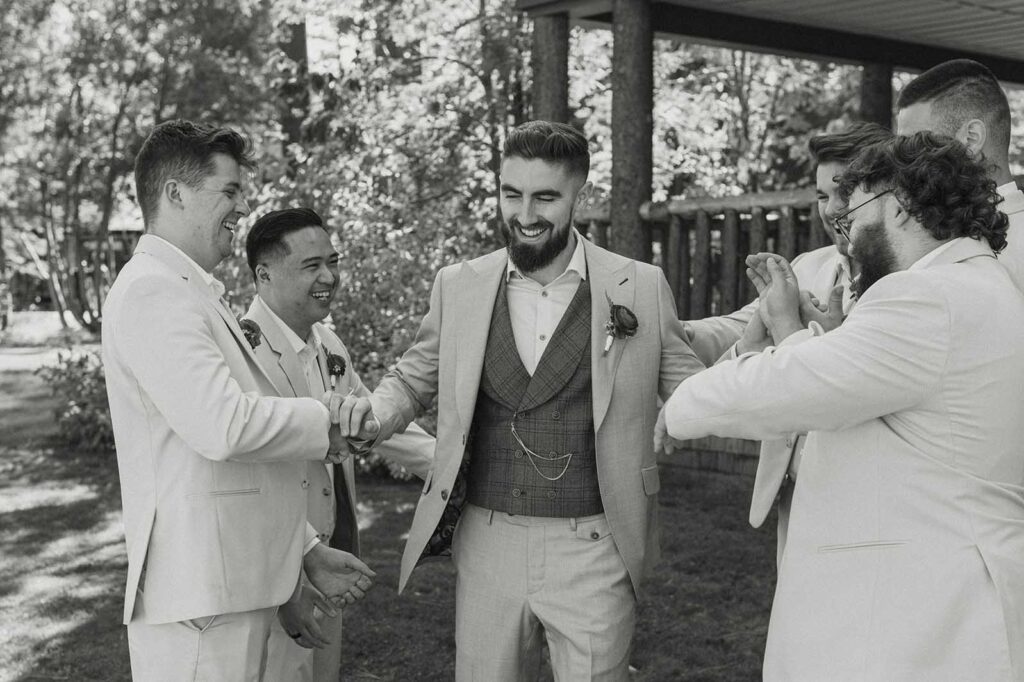 Groom laughing while walking through groomsmen and getting shoved by them at Valhalla in Lake Tahoe