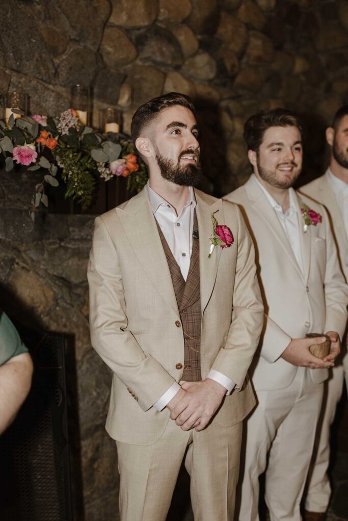 Groom watching bride walk down aisle in front of rock wall during wedding ceremony at Valhalla in Lake Tahoe