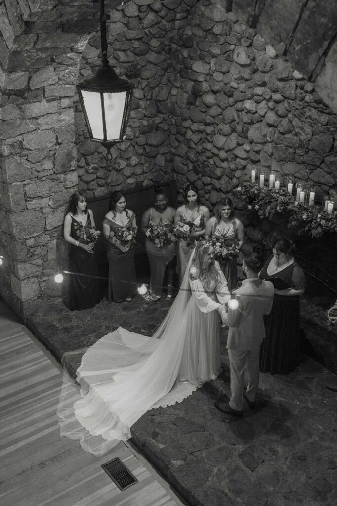 Couple holding hands during wedding ceremony underneath stone archway at Valhalla in Lake Tahoe