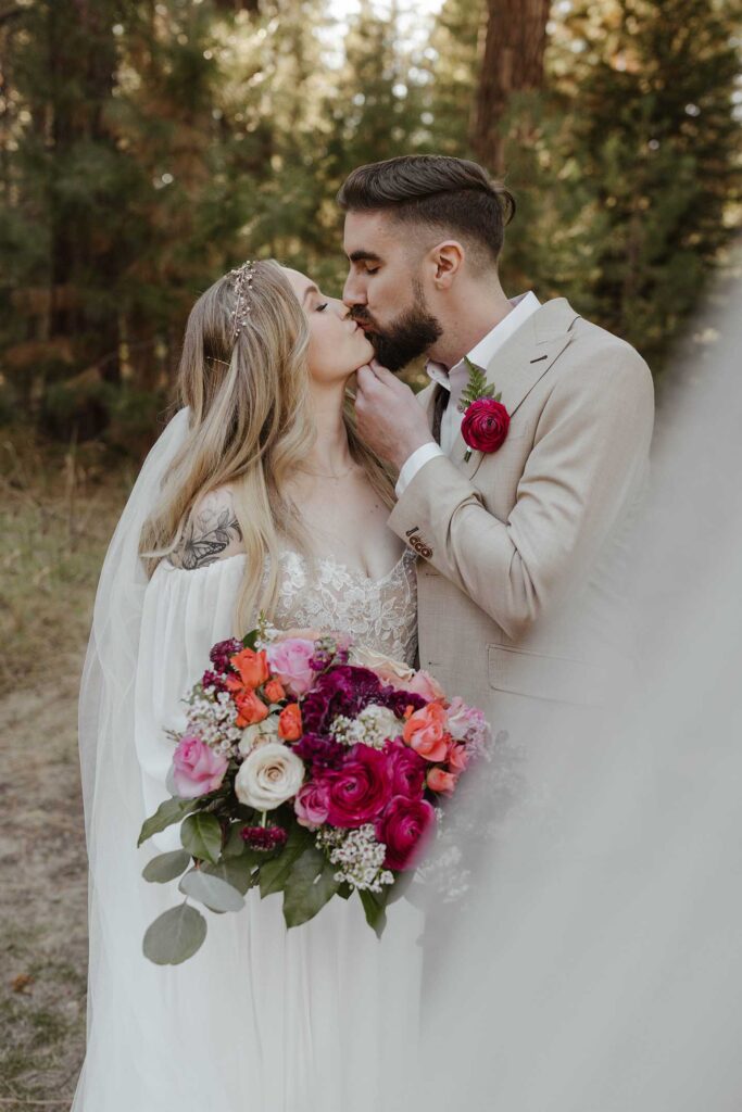Groom holding brides chin while kissing and wedding veil obscures camera lens at Valhalla in Lake Tahoe