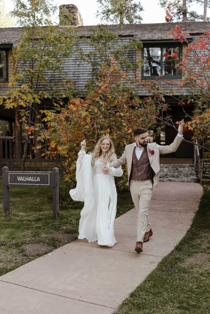Wedding couple holding hands while walking down pathway away from wooden building at Valhalla in Lake Tahoe