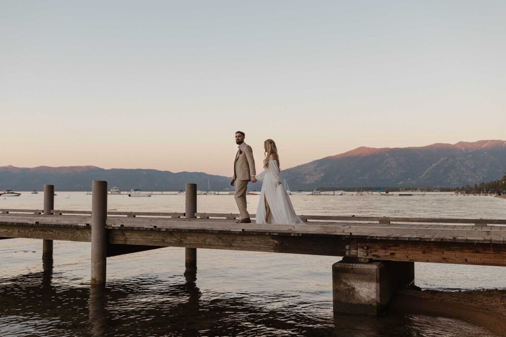 Wedding couple holding hands while walking along wooden dock on Lake Tahoe at Valhalla