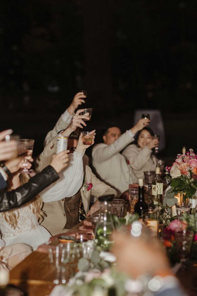 Wedding guests holding up drinks to cheer during wedding reception at Valhalla in Lake Tahoe