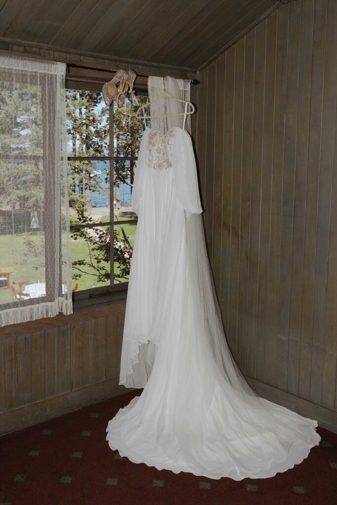 Wedding dress hanging on white hangar in front of window at Valhalla in Lake Tahoe
