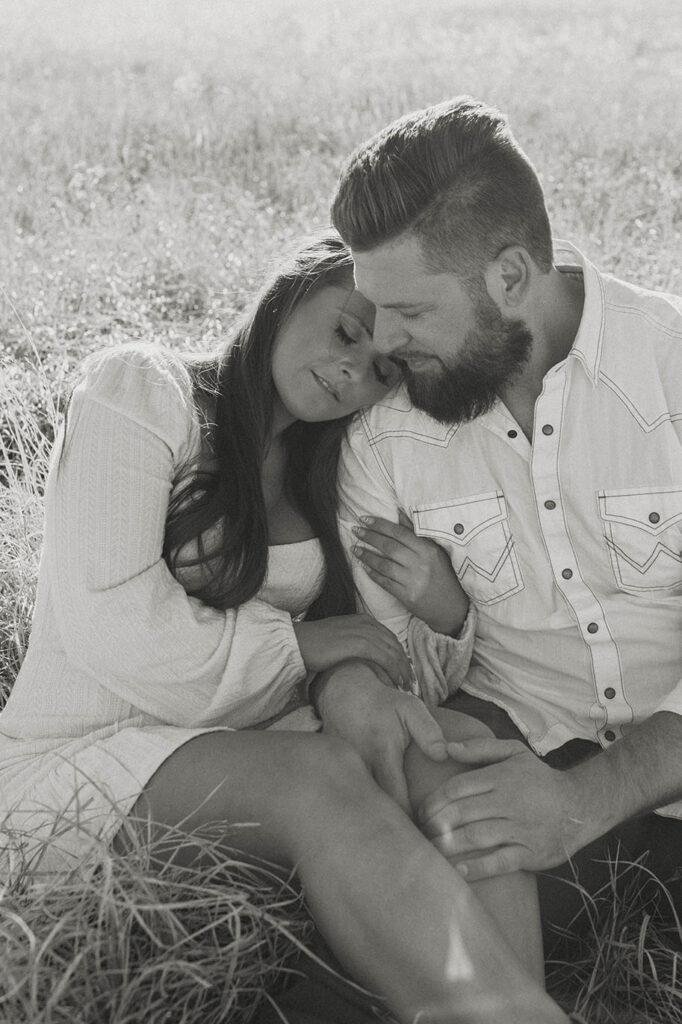 Woman hugging and leaning onto boyfriends arm while sitting together in golden field in Lake Tahoe