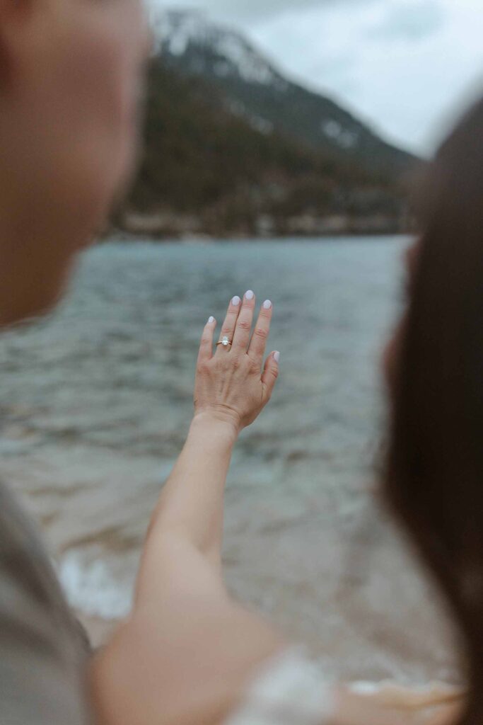 Couple admiring engagement ring on woman's outstretched hand with Lake Tahoe in background