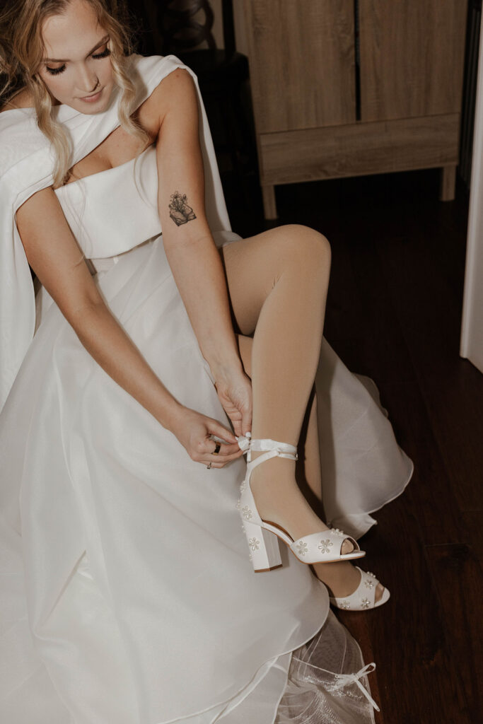 Bride fastening wedding shoes while sitting in chair for elopement in Emerald Bay