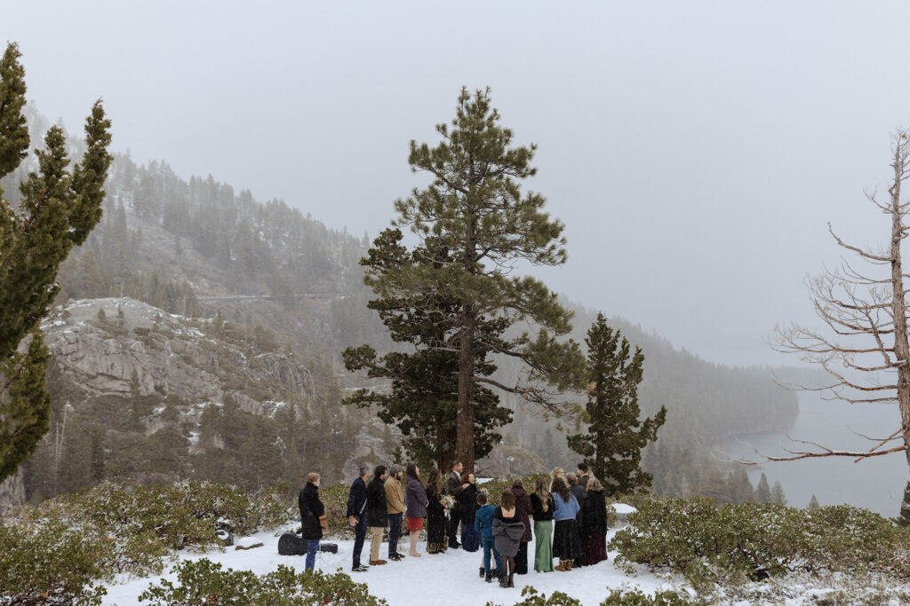 Snowy elopement in Emerald Bay with guests and Lake Tahoe in background