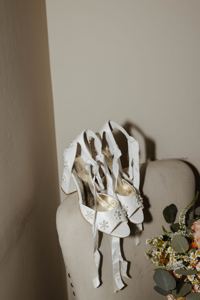 White wedding shoes with ribbons sitting on edge of chair for elopement in Emerald Bay