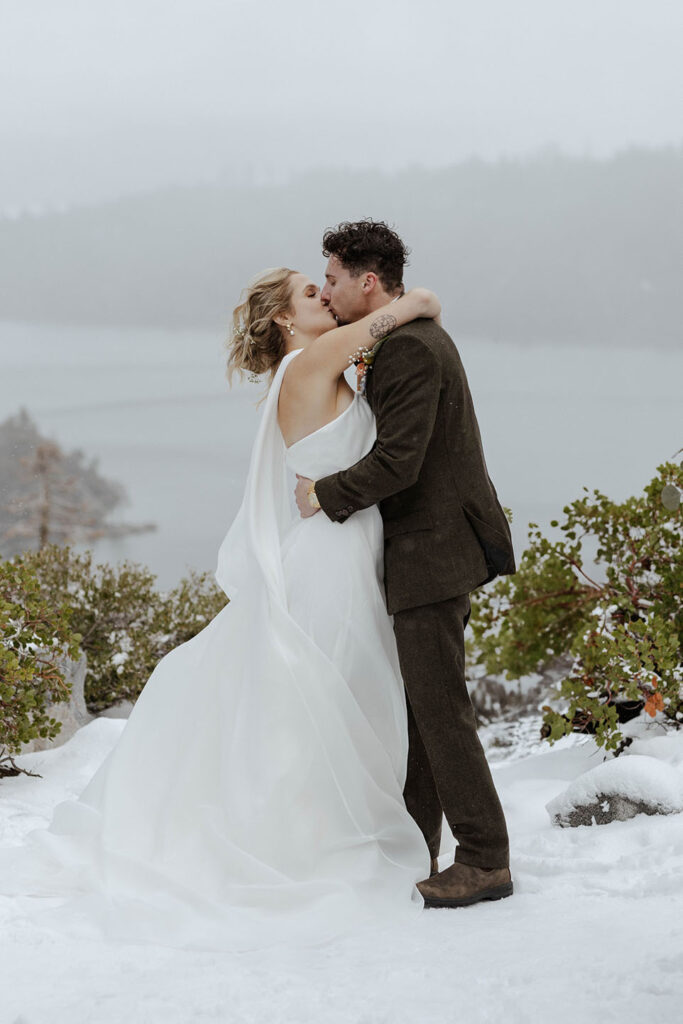 Elopement couple holding each other and kissing in snow after ceremony in Emerald Bay