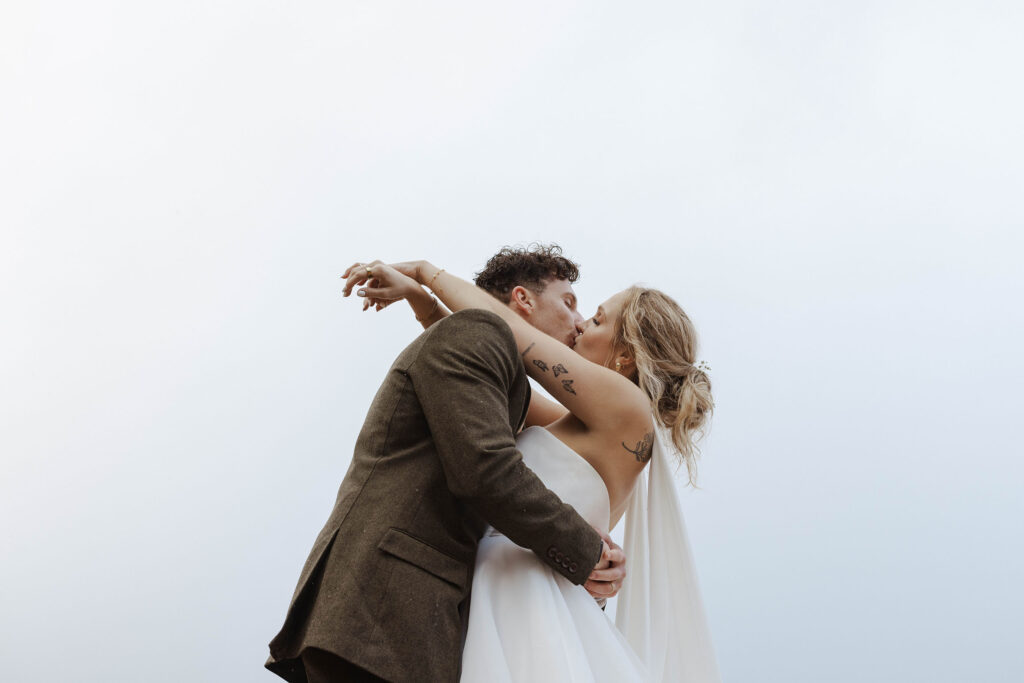 Elopement couple kissing while hugging each other with sky in background in Emerald Bay
