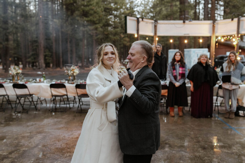 Elopement bride dancing with dad during reception in Emerald Bay with guests and string lights in background