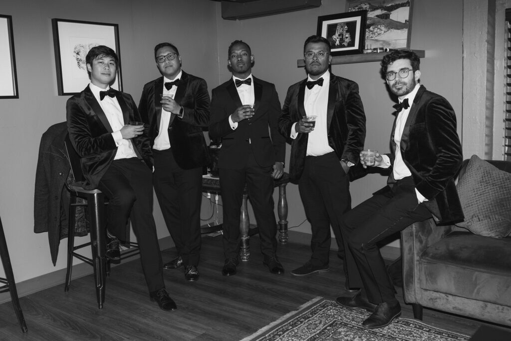 Groom and groomsmen in wedding attire posing with drinks in hand inside at the Tannenbaum