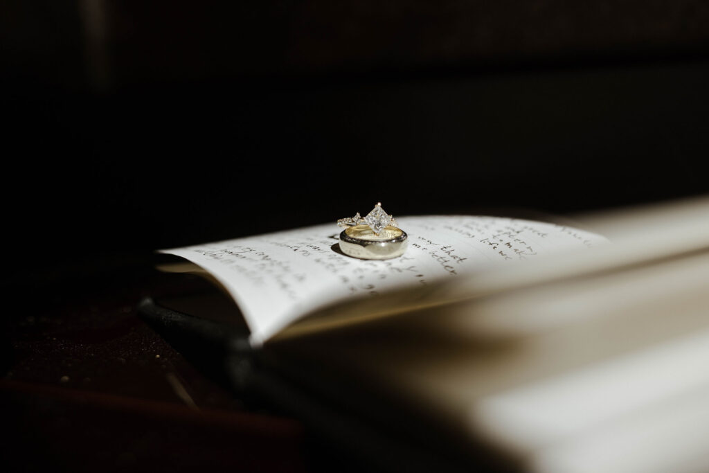 Close up of wedding rings on vow book with light coming in from side