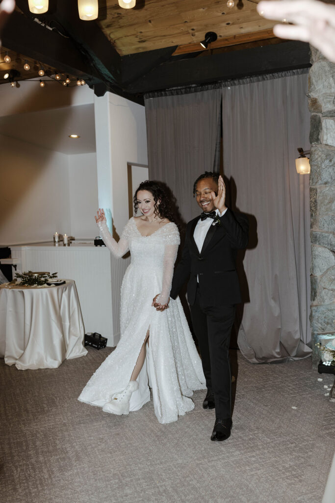 Wedding couple walking into reception during grand entrance at the Tannenbaum smiling and waving