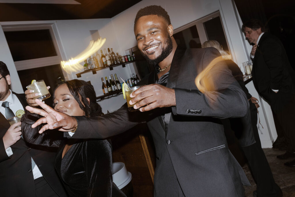 Wedding guests holding drinks and dancing during reception with lights blurring at the Tannenbaum