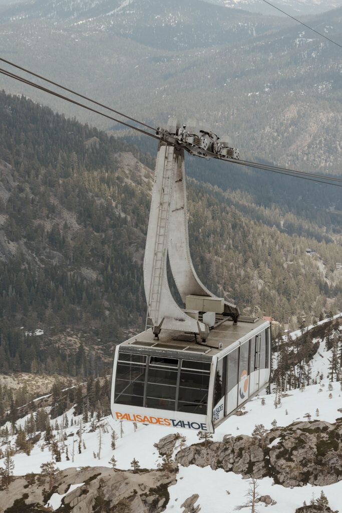 Tram car going down the hill at Palisades Tahoe with pine trees and snow in background
