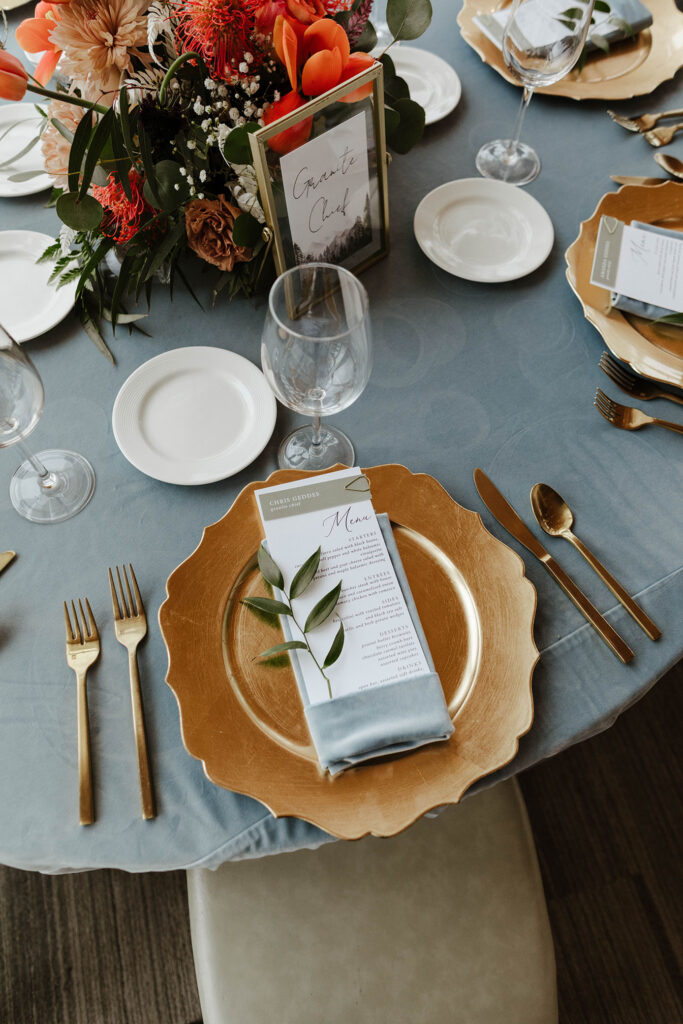 Gold plate and utensils on wedding reception table with gray tablecloth at Palisades Tahoe