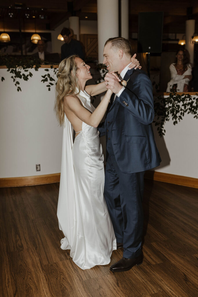 Wedding couple dancing together on wooden dance floor while smiling at each other during reception at Palisades Tahoe