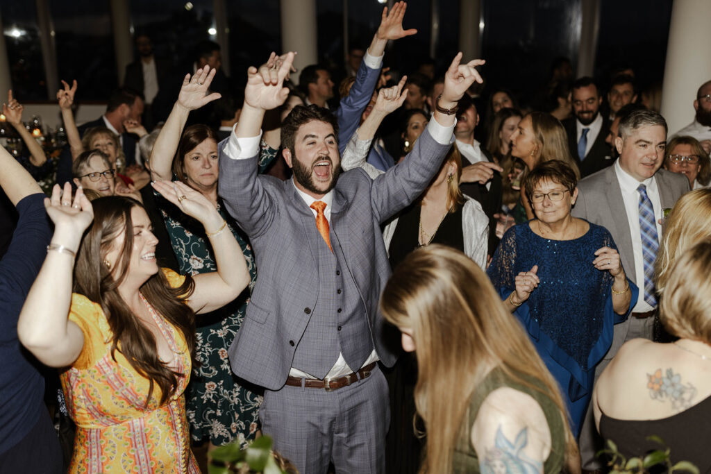 Wedding guests dancing and celebrating during with hands in the air during reception at Palisades Tahoe