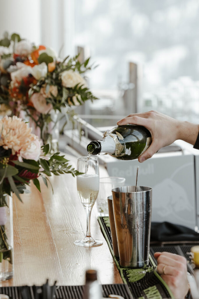 Champagne being poured into glass on wooden table next to floral decorations at Palisades Tahoe