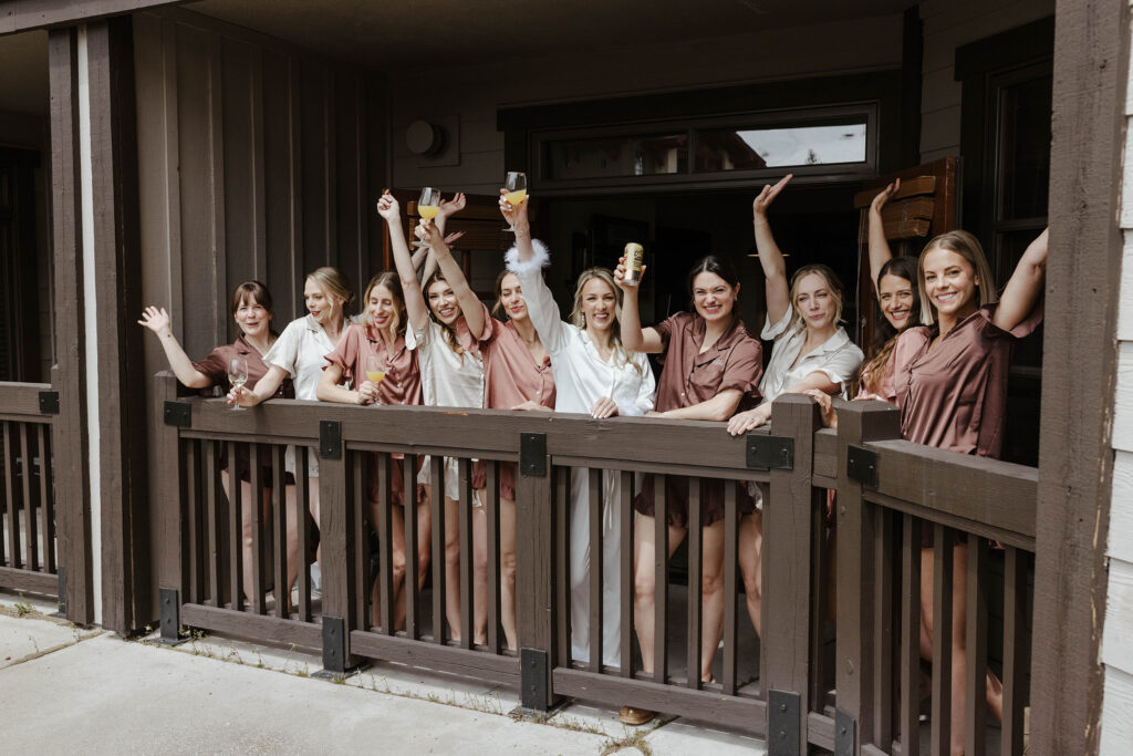 Wedding bride and bridesmaids holding drinks up while celebrating on patio at Palisades Tahoe
