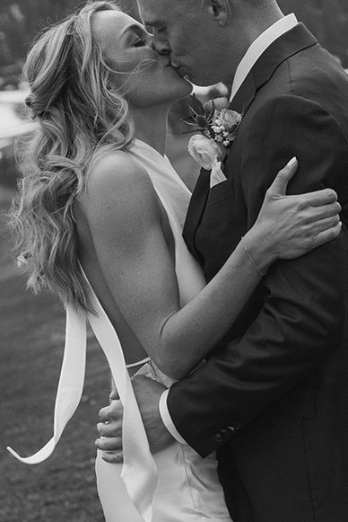 Close up of wedding couple holding each other and kissing in grassy field