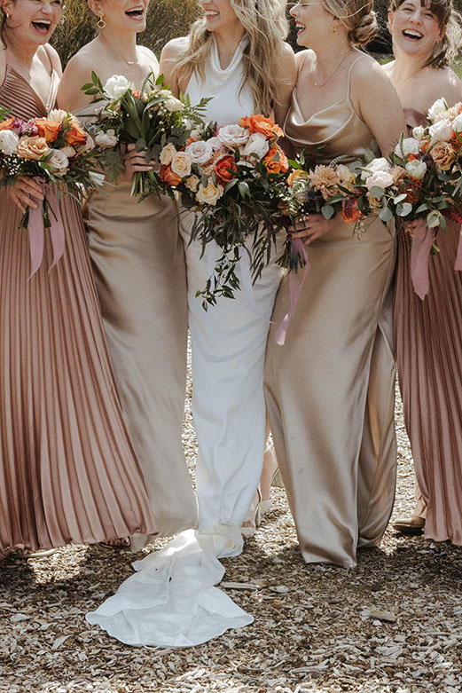 Close up of bride and bridesmaids holding colorful floral bouquets while laughing together at Palisades Tahoe