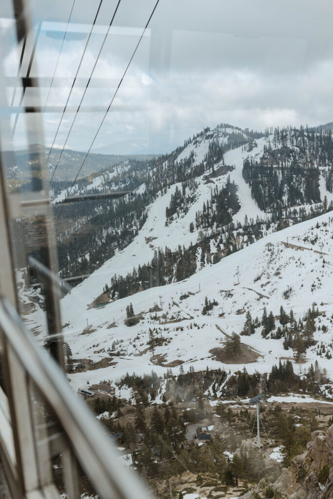Looking out tram car window at ski runs on snowy mountains at Palisades Tahoe