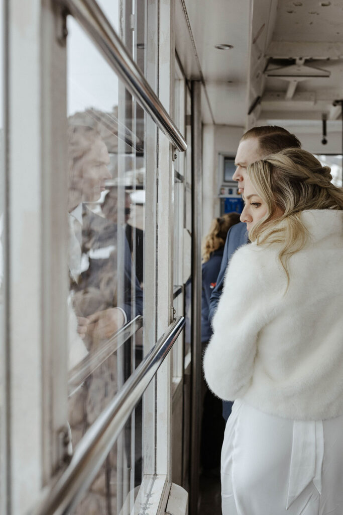 Wedding couple holding each other while looking out side of tram car window at Palisades Tahoe