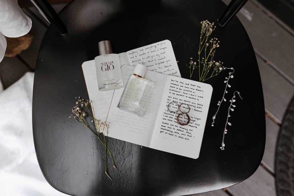 Close up of vow books and wedding rings on top of them next to other details on black metal chair