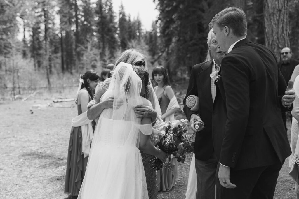 Wedding couple hugging parents after ceremony in South Lake Tahoe with bridesmaids and pine trees in background