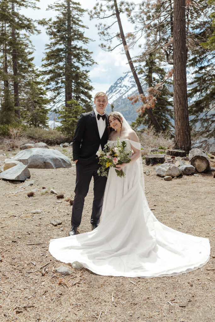 Wedding couple smiling while looking at the camera and holding each other with pine trees behind them in South Lake Tahoe