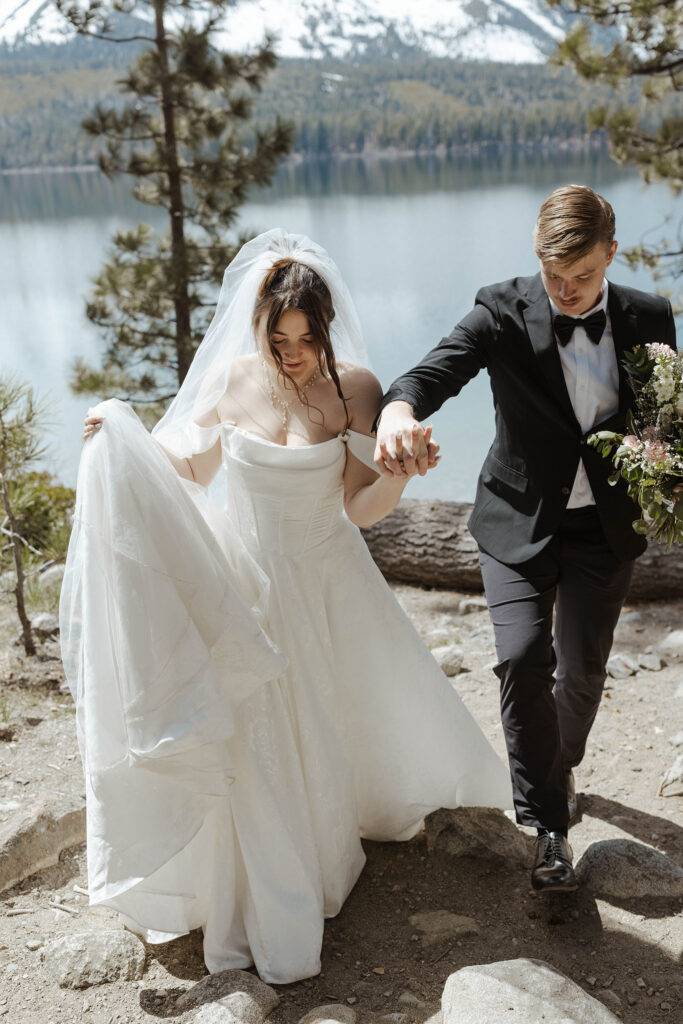 Wedding couple holding hands while walking up rocky trail together towards camera in South Lake Tahoe