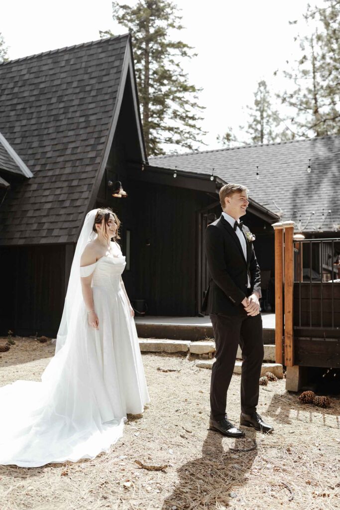 Bride in wedding dress walking up to groom who is facing away during first look at South Lake Tahoe