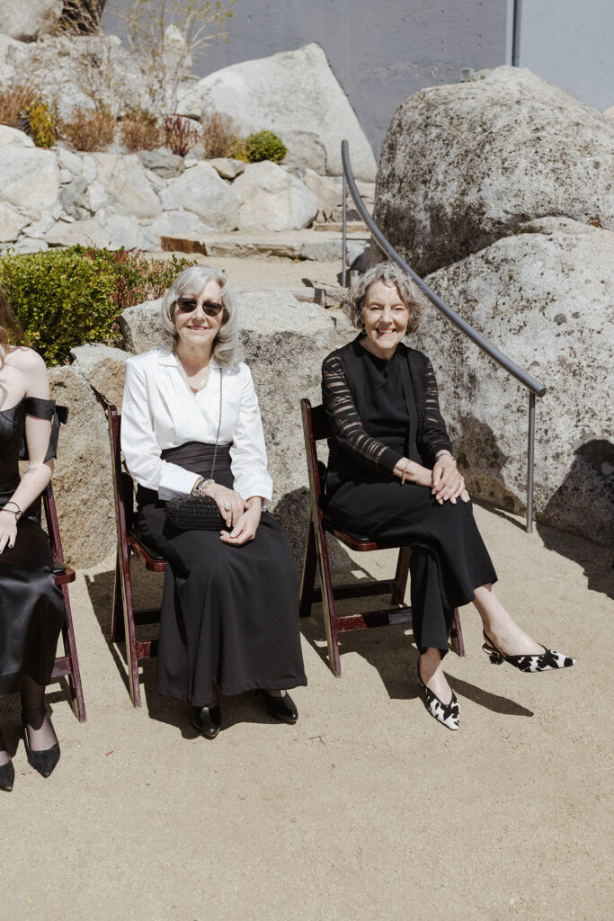 two grandmothers sitting in chairs smiling at the camera at a wedding ceremony at tahoe blue estate