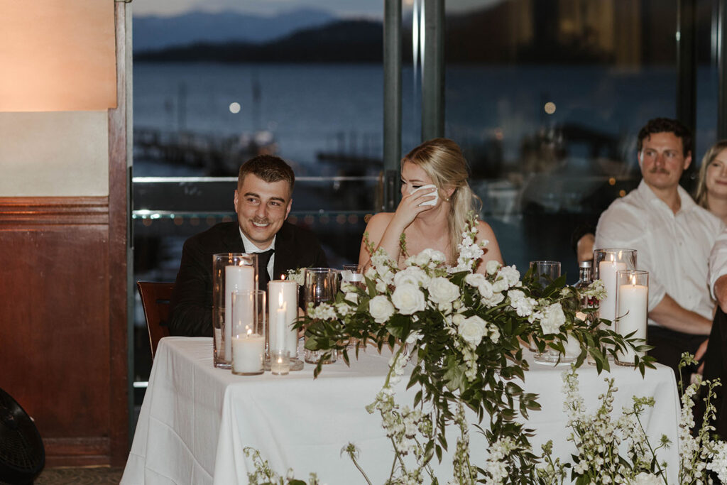 bride wiping a tear and groom laughing and smiling during speeches at riva grill