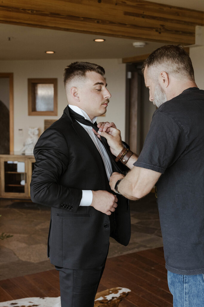 man helping the groom get ready for his wedding day at tahoe blue estate
