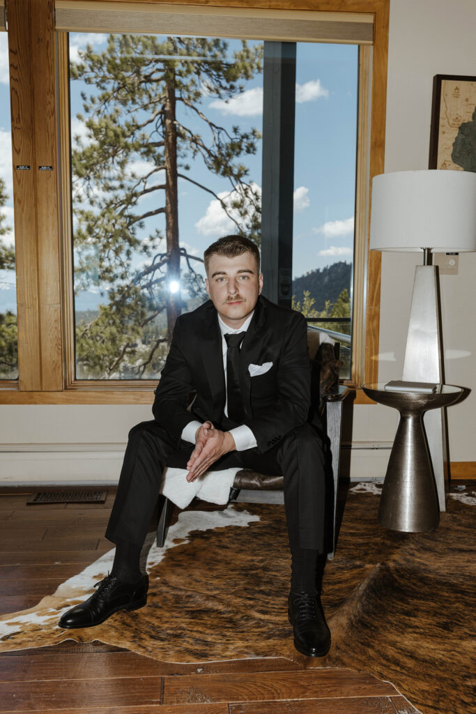 groom sitting in a chair looking at the camera wearing a black suit at tahoe blue estate
